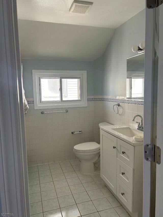 bathroom with lofted ceiling, plenty of natural light, toilet, and vanity