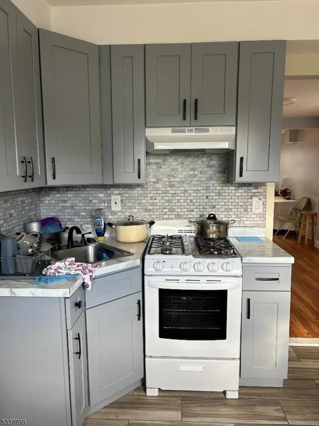 kitchen with wood-type flooring, white range with gas cooktop, sink, and gray cabinetry