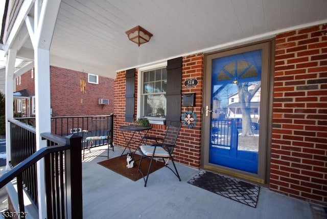 property entrance featuring a porch and brick siding