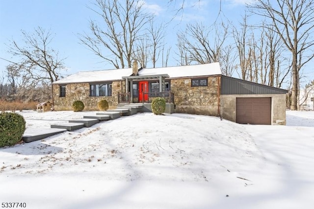 view of front of property featuring a garage, stone siding, and a chimney