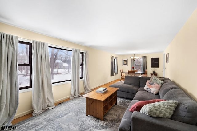 living area featuring a chandelier, baseboards, and wood finished floors