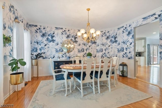 dining area with crown molding, wainscoting, a notable chandelier, and wallpapered walls