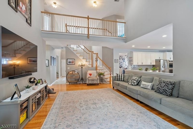 living area with light wood finished floors, a high ceiling, and stairway