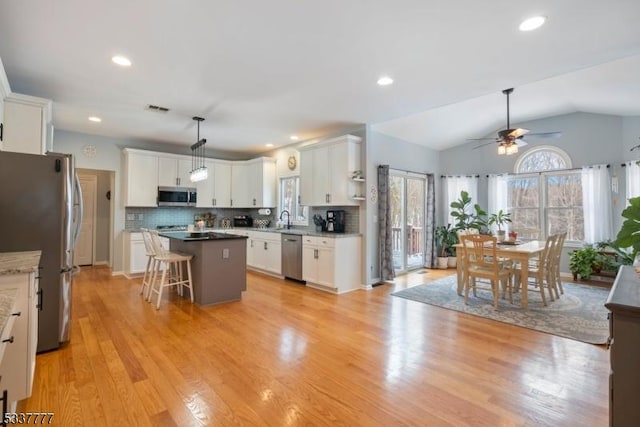 kitchen with a sink, visible vents, white cabinetry, appliances with stainless steel finishes, and a center island