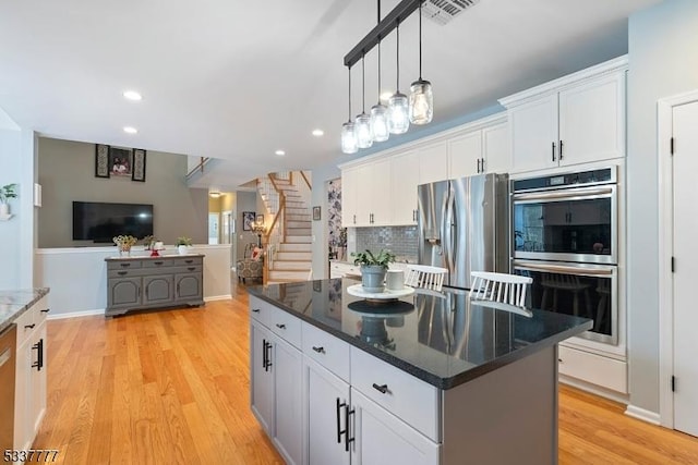 kitchen with visible vents, decorative backsplash, stainless steel appliances, light wood-style floors, and white cabinetry