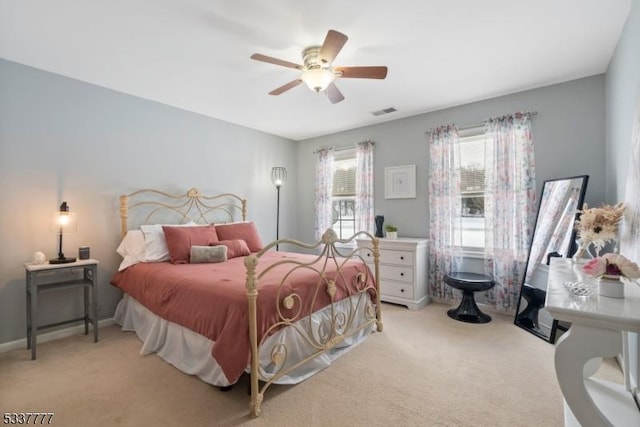 bedroom with ceiling fan, visible vents, baseboards, and light colored carpet