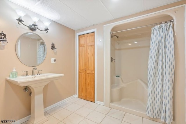 bathroom with a shower with shower curtain, tile patterned flooring, and baseboards