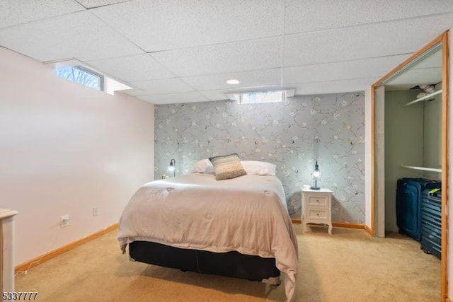 bedroom with an accent wall, carpet floors, a paneled ceiling, and baseboards