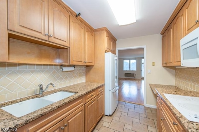 kitchen with sink, light stone counters, a wall mounted AC, white appliances, and decorative backsplash