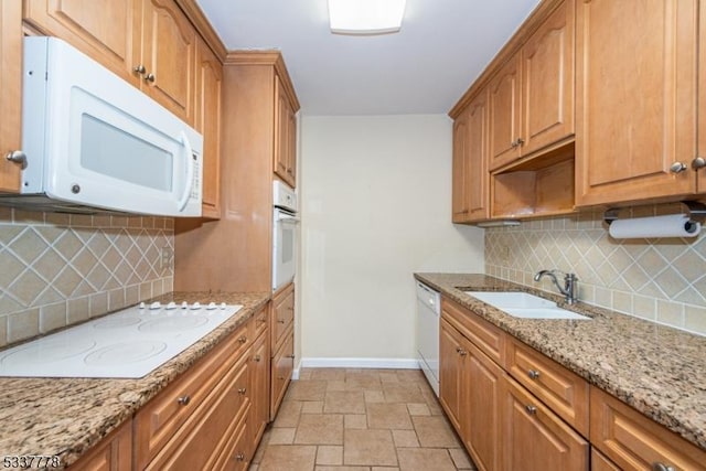 kitchen featuring sink, white appliances, light stone countertops, and decorative backsplash