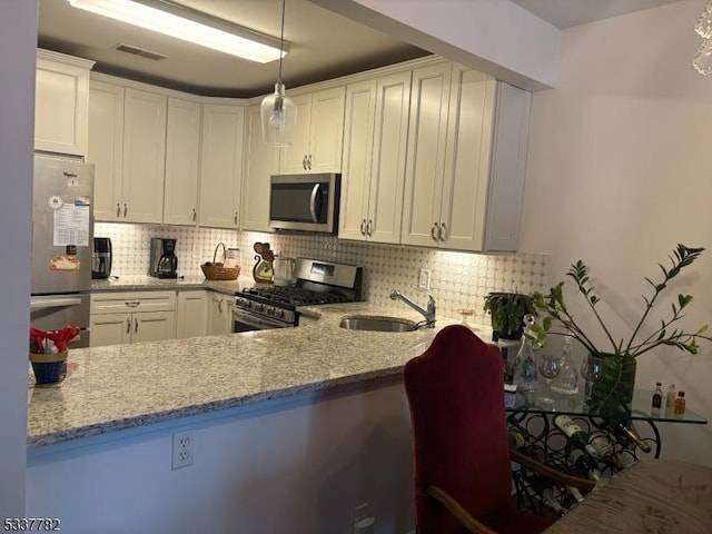 kitchen featuring decorative light fixtures, light stone countertops, white cabinets, and appliances with stainless steel finishes