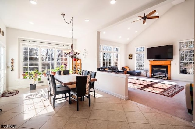 dining space with light tile patterned flooring, ceiling fan with notable chandelier, and high vaulted ceiling