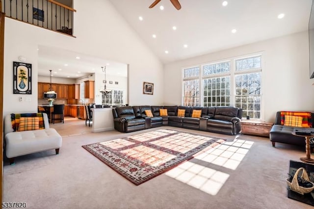 carpeted living room with ceiling fan and high vaulted ceiling