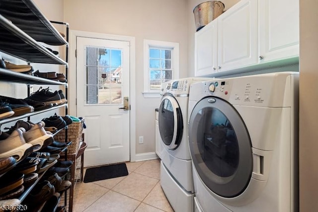 clothes washing area with independent washer and dryer, light tile patterned floors, and cabinets