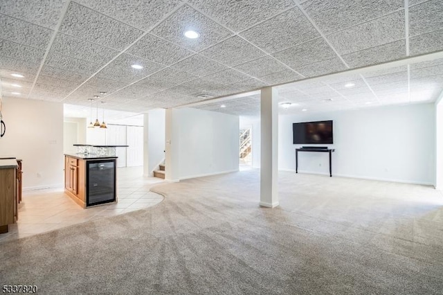 basement with wine cooler, light carpet, and a paneled ceiling