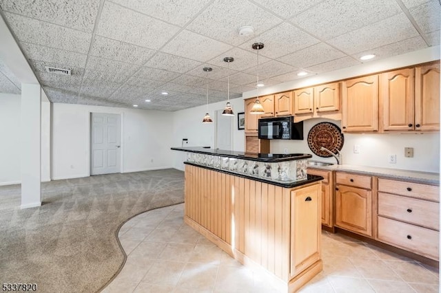 kitchen with a paneled ceiling, light brown cabinetry, decorative light fixtures, a center island, and light colored carpet