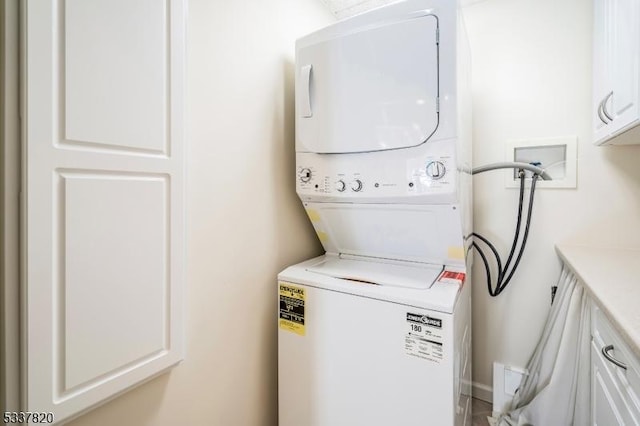 clothes washing area featuring cabinets and stacked washer / drying machine