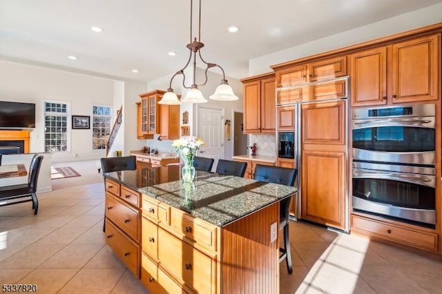 kitchen featuring light tile patterned flooring, a kitchen island, a breakfast bar, pendant lighting, and stainless steel double oven