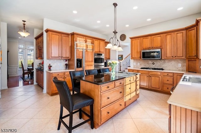 kitchen with a kitchen island, appliances with stainless steel finishes, a kitchen bar, and decorative light fixtures