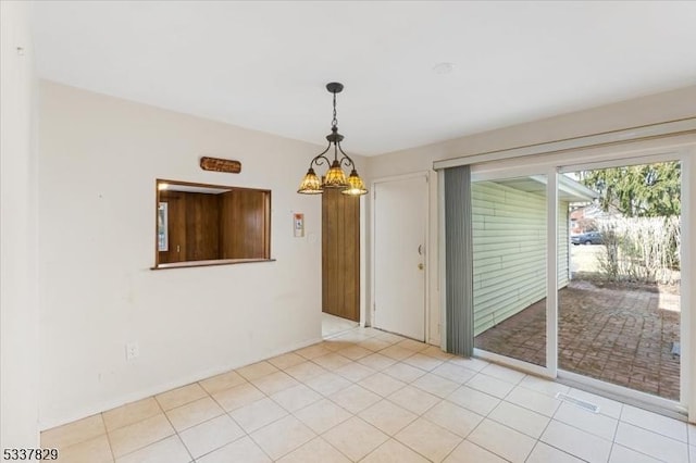 empty room featuring a chandelier and light tile patterned flooring