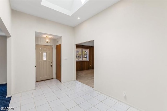 entrance foyer with a skylight, recessed lighting, light tile patterned floors, and light colored carpet