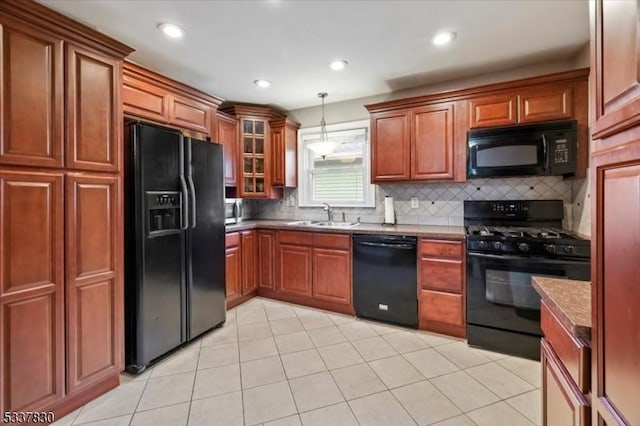 kitchen featuring brown cabinetry, decorative backsplash, hanging light fixtures, black appliances, and a sink