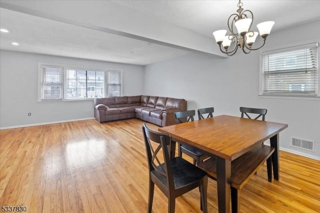 dining space with an inviting chandelier, light wood-style flooring, baseboards, and visible vents