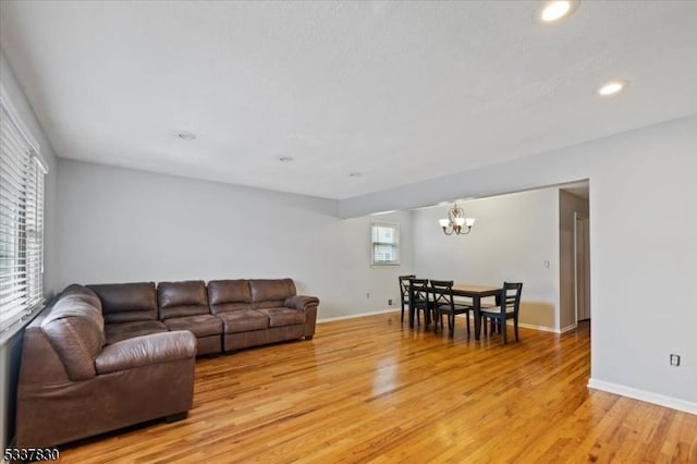 living room with recessed lighting, an inviting chandelier, light wood-type flooring, and baseboards