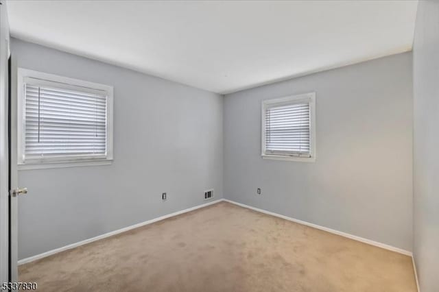 carpeted empty room with visible vents and baseboards