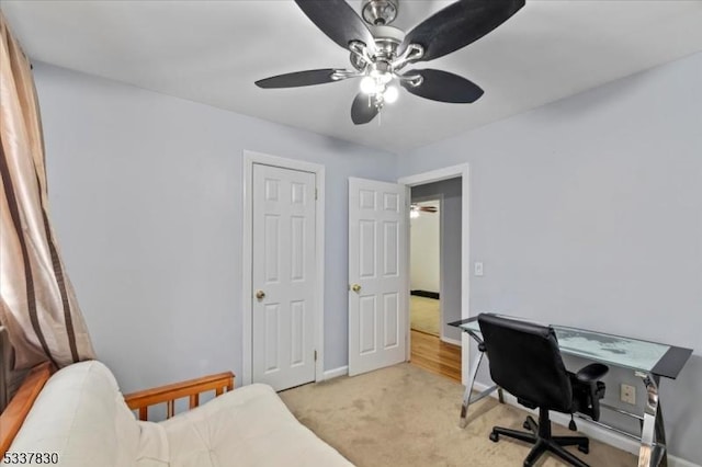 office featuring ceiling fan, baseboards, and light carpet