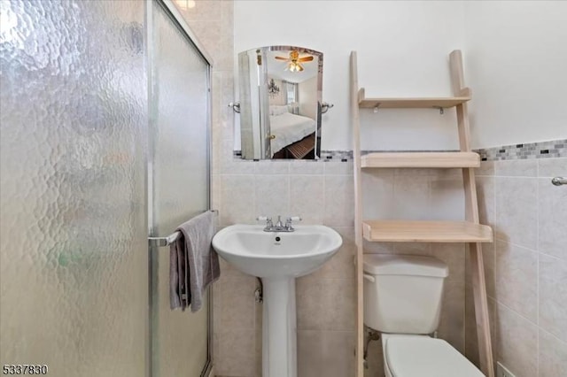 ensuite bathroom with a stall shower, toilet, tile walls, and ensuite bath