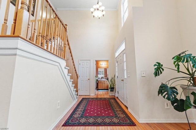 foyer entrance featuring crown molding, stairway, baseboards, and wood finished floors