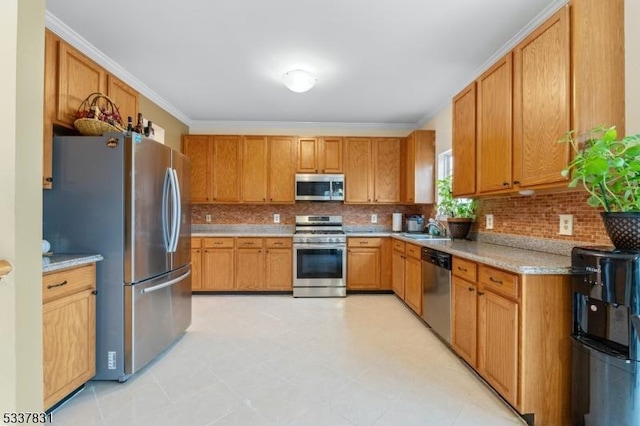 kitchen with brown cabinetry, decorative backsplash, appliances with stainless steel finishes, ornamental molding, and a sink