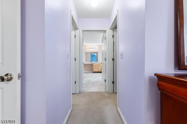 hall featuring light carpet and baseboards