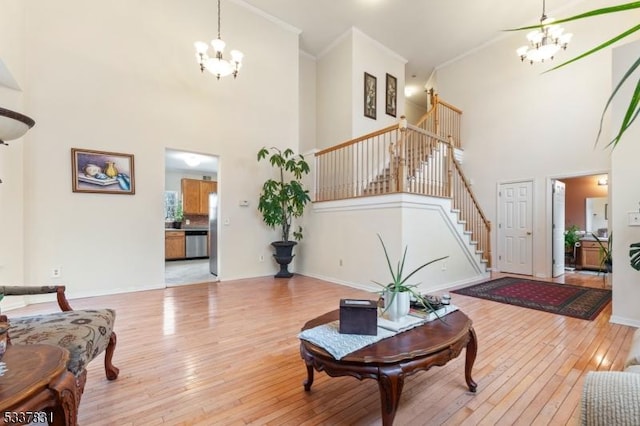 living area featuring a chandelier, baseboards, light wood-style floors, stairway, and crown molding