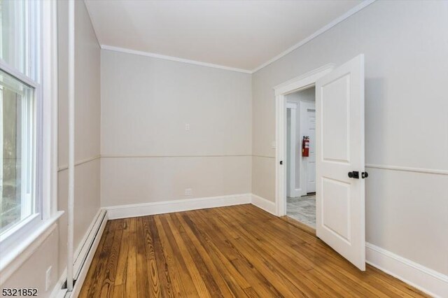 empty room with crown molding, hardwood / wood-style flooring, and a baseboard radiator