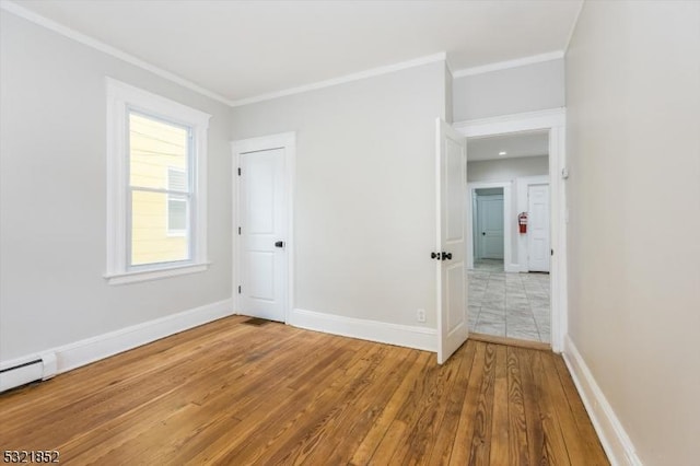 empty room featuring crown molding, a baseboard radiator, and hardwood / wood-style flooring