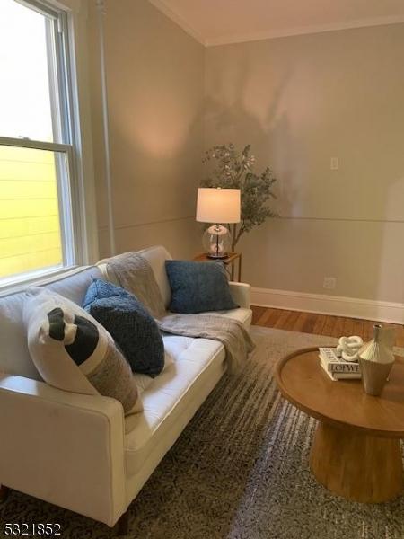 living room featuring ornamental molding and wood-type flooring