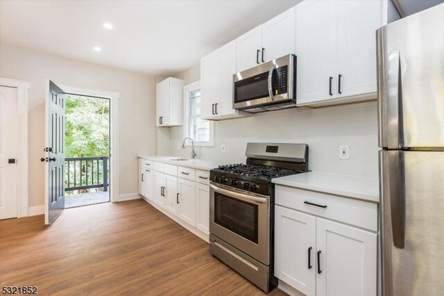 kitchen with white cabinetry, appliances with stainless steel finishes, sink, and light hardwood / wood-style flooring