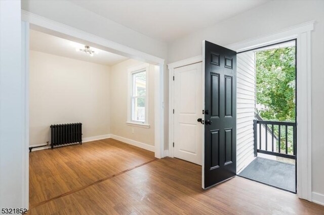 foyer with radiator heating unit, hardwood / wood-style floors, and a wealth of natural light