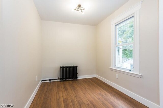 spare room with hardwood / wood-style flooring and radiator heating unit