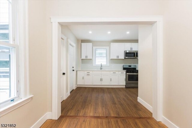 kitchen featuring dark hardwood / wood-style flooring, sink, white cabinets, and appliances with stainless steel finishes