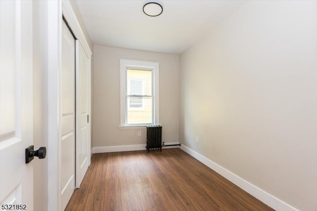 unfurnished bedroom featuring radiator, dark wood-type flooring, and a closet