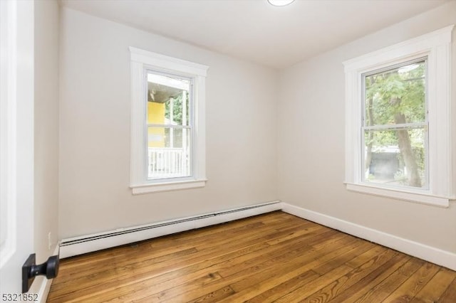 unfurnished room featuring a baseboard radiator, light wood-type flooring, and a wealth of natural light