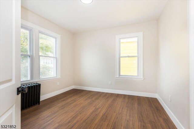 spare room featuring dark hardwood / wood-style flooring and radiator heating unit