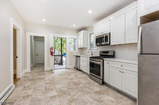 kitchen with baseboard heating, sink, white cabinets, and appliances with stainless steel finishes