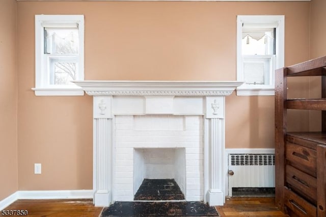 room details featuring a brick fireplace, radiator, and hardwood / wood-style floors