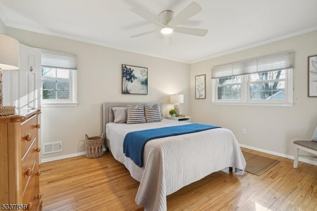 bedroom featuring ornamental molding, baseboards, visible vents, and light wood finished floors