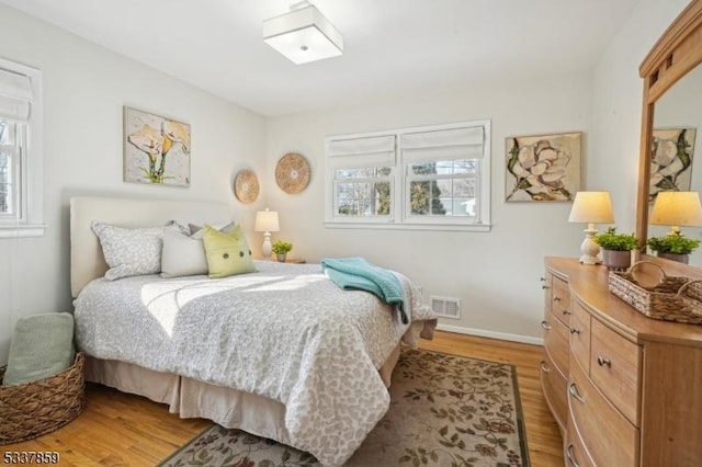 bedroom featuring visible vents, light wood-style flooring, and baseboards