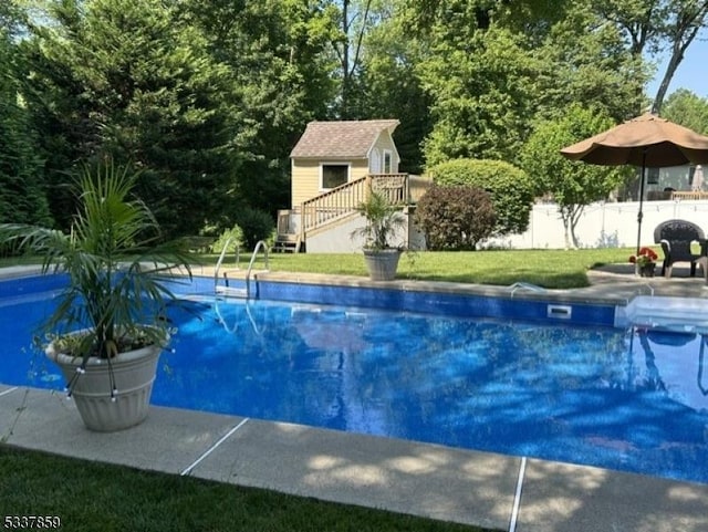 view of swimming pool featuring stairs, a lawn, an outbuilding, and fence